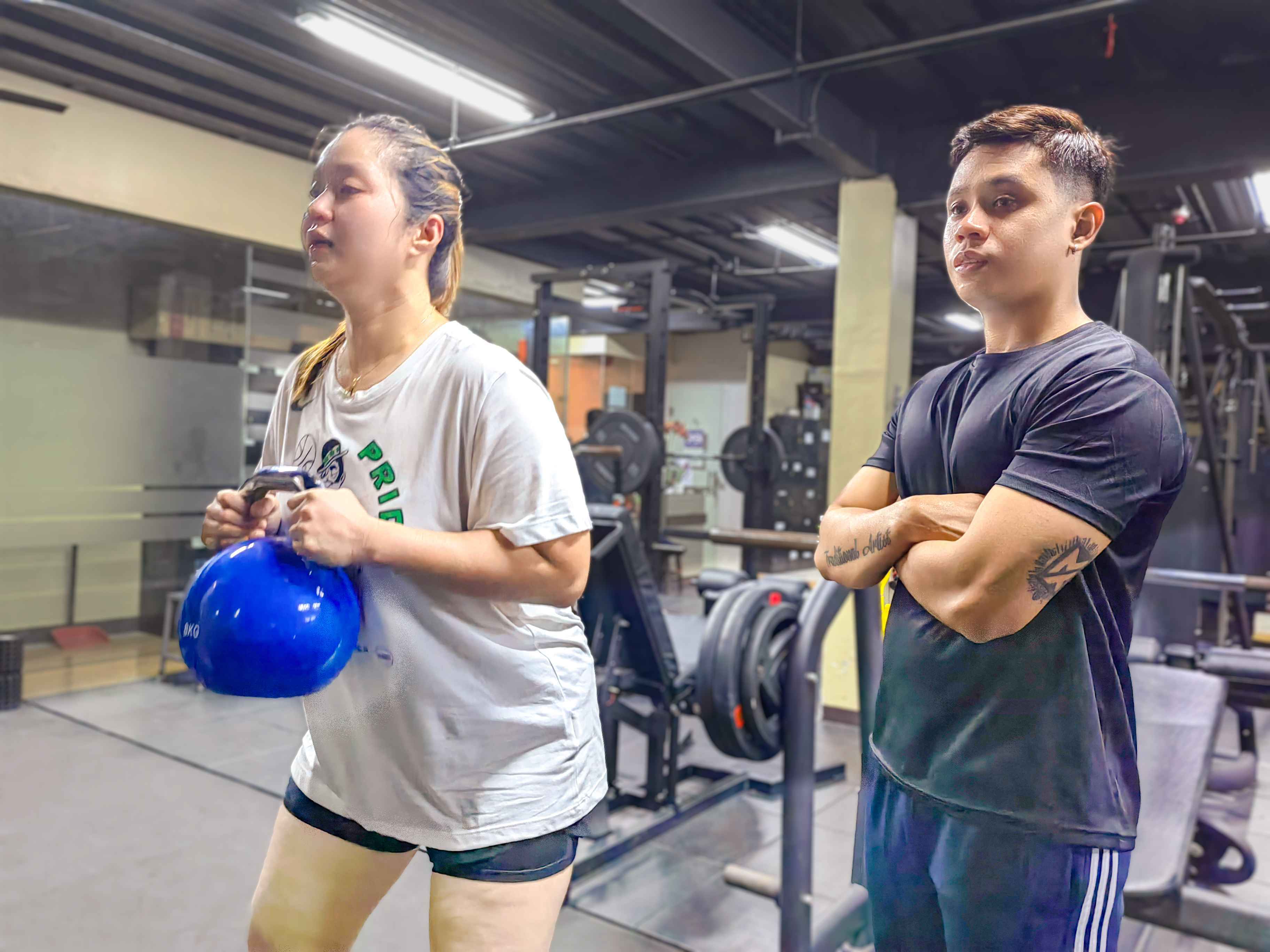 Member holding kettlebell and fitness coach in a training session